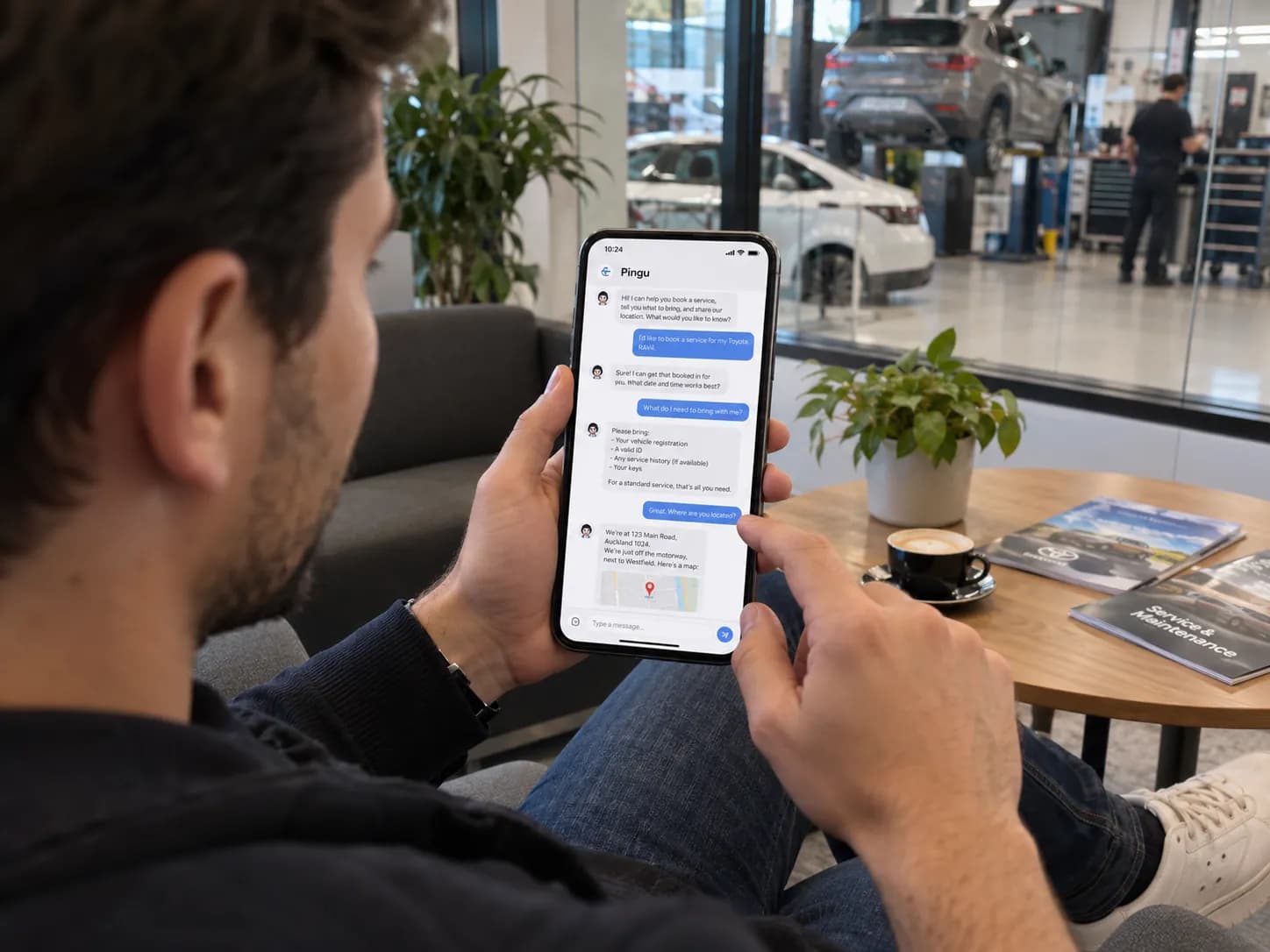 Workshop customer in the waiting area checking service details with Pingu on a phone